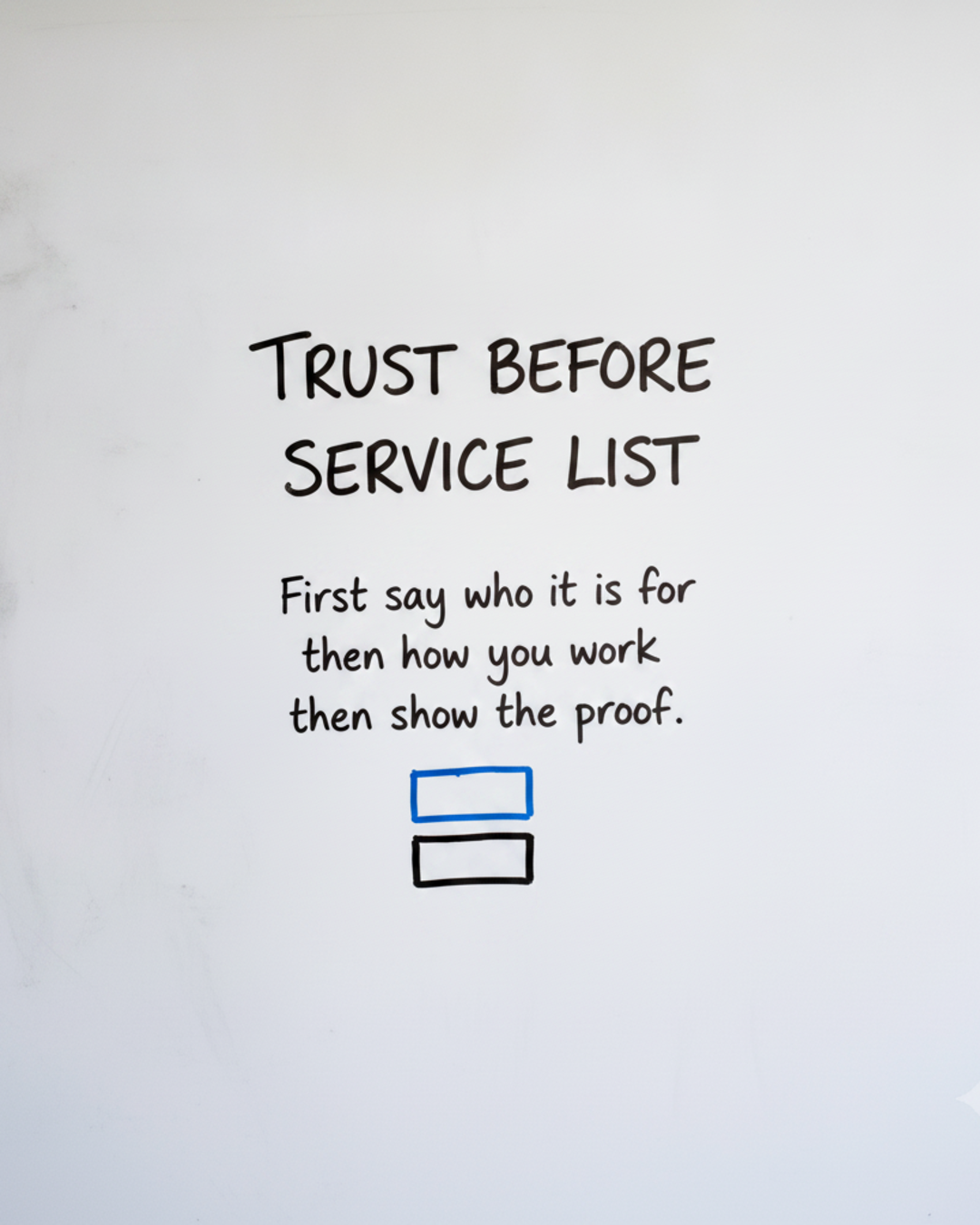 Whiteboard with the words Trust before service list written in black marker above two small empty boxes, one blue and one black