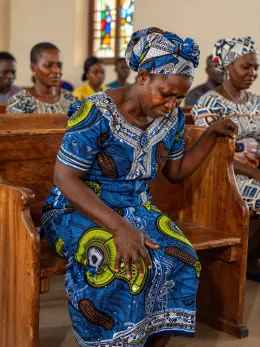 Nigerian woman struggling to kneel down at church