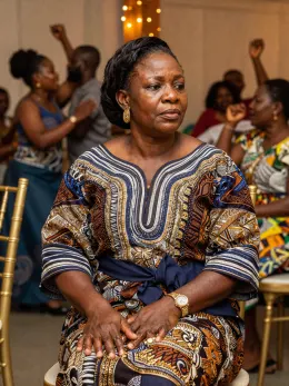 Nigerian woman sitting out while others dance at an owambe party