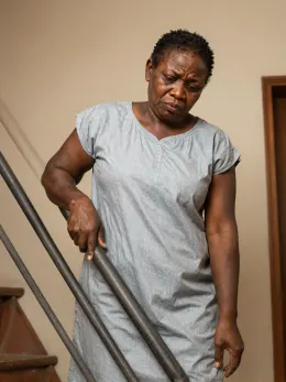 Nigerian woman holding the rail tightly while climbing stairs