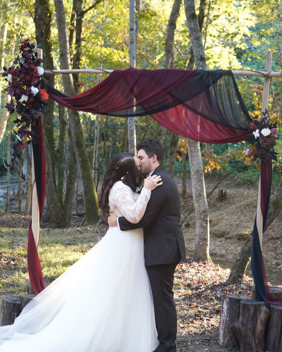 Nick and Makenzie kissing under the ceremony arch
