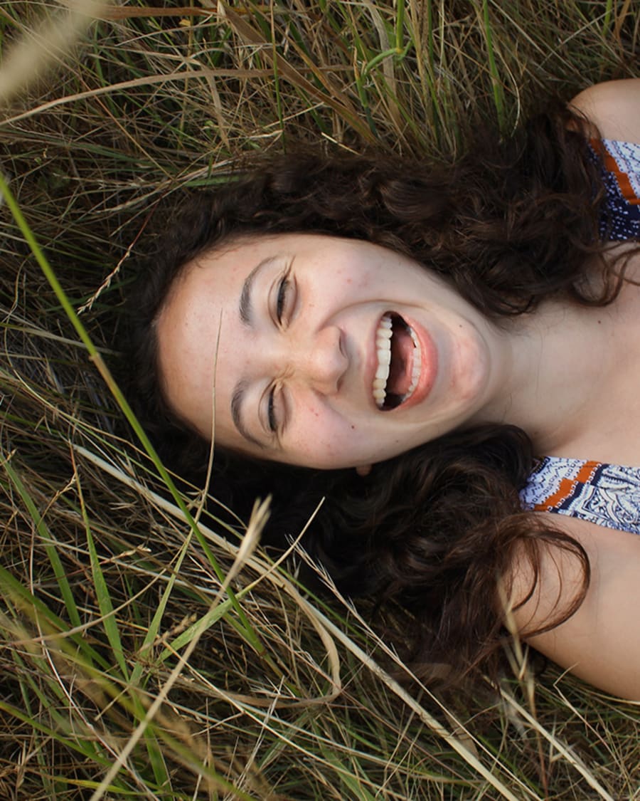 A graduate laughing in tall grass