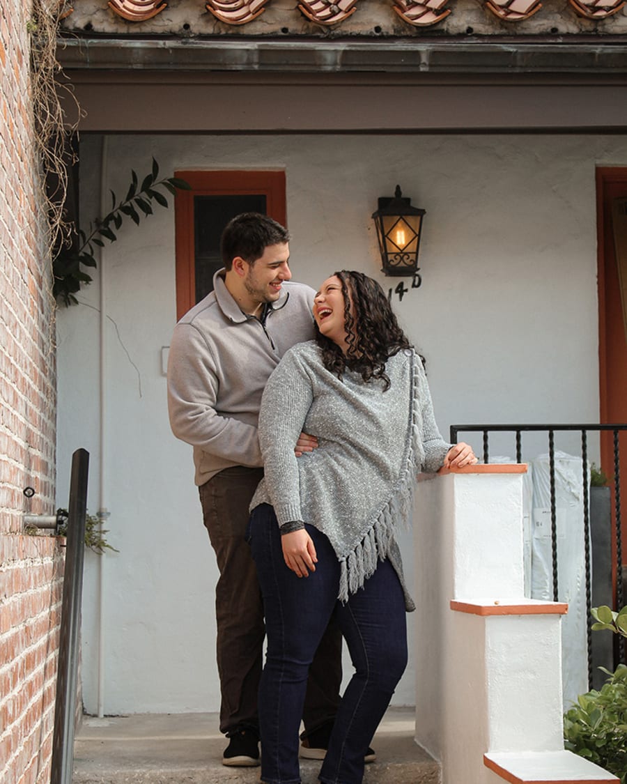 An engaged couple laughing in a doorway