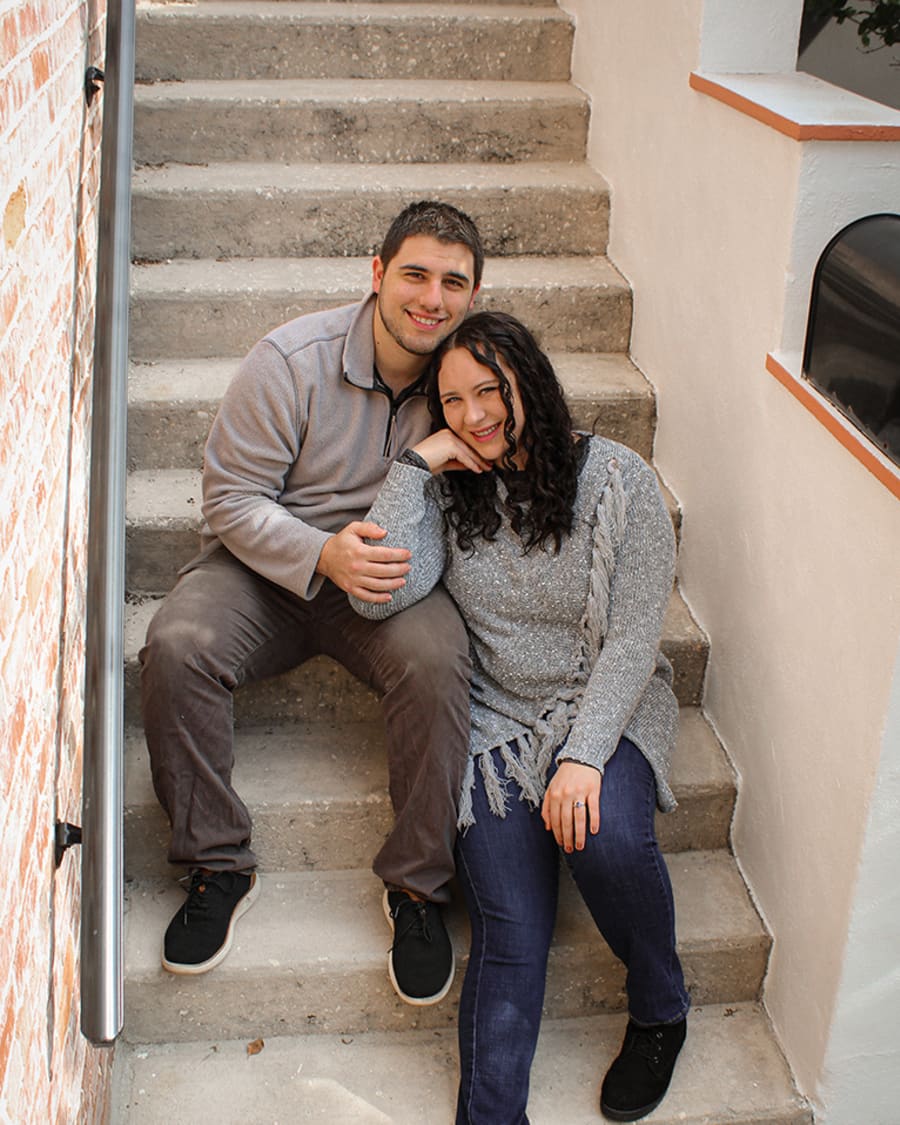 An engaged couple sitting on a stairway
