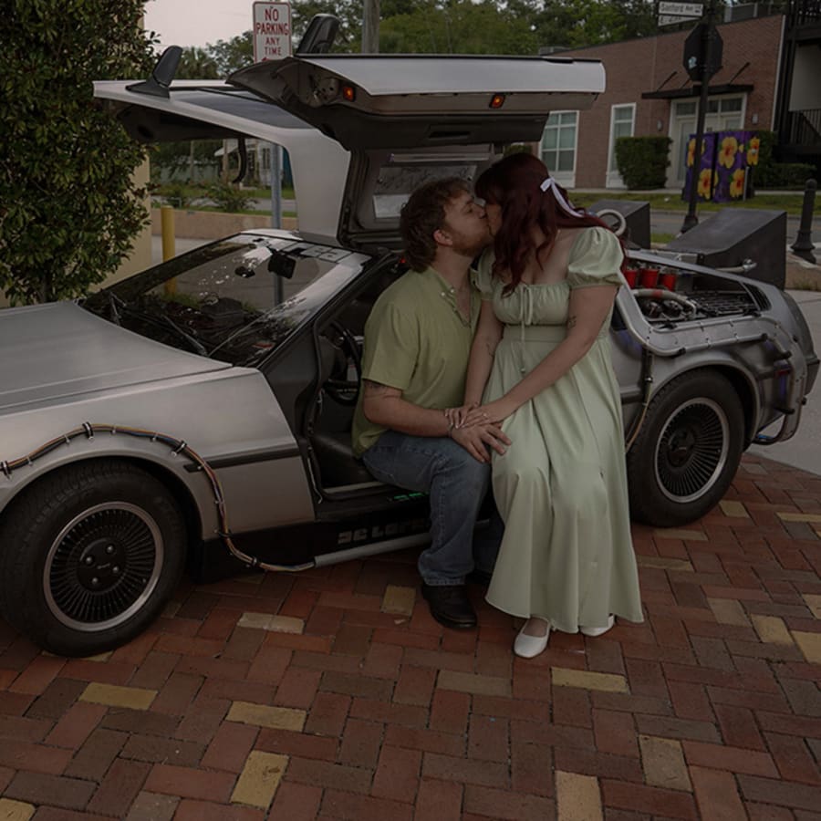 An engaged couple with a vintage car