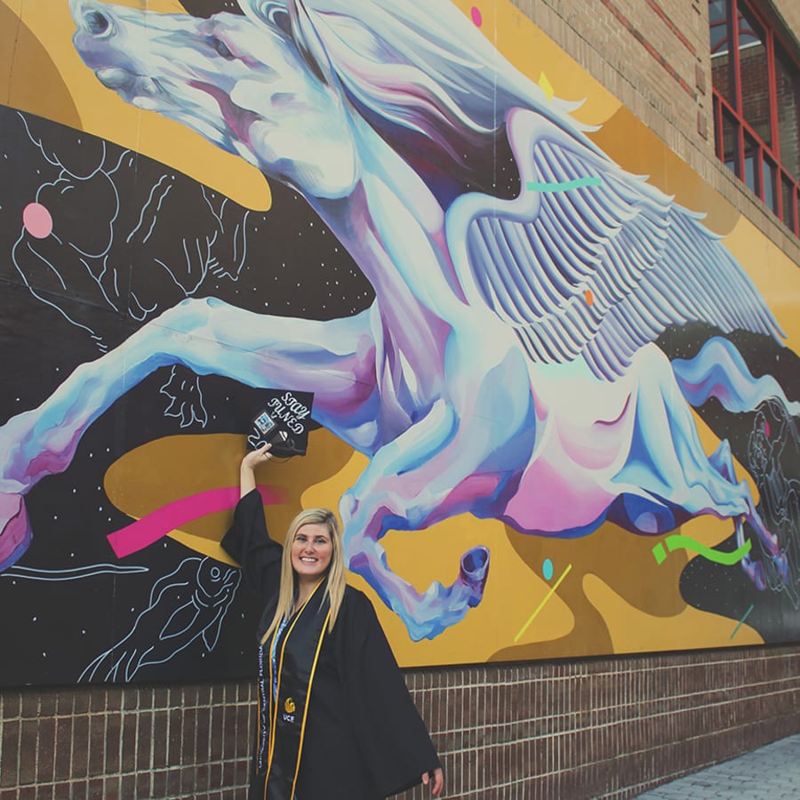 A graduate by the UCF pegasus wall