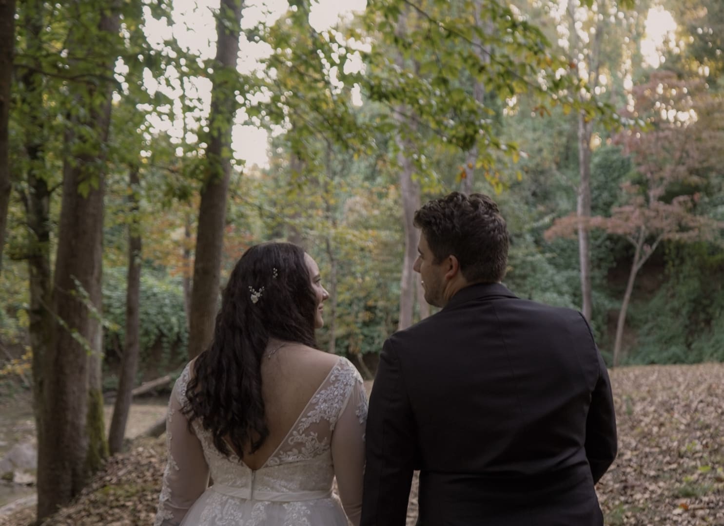 A bride and groom together in the woods, seen from behind