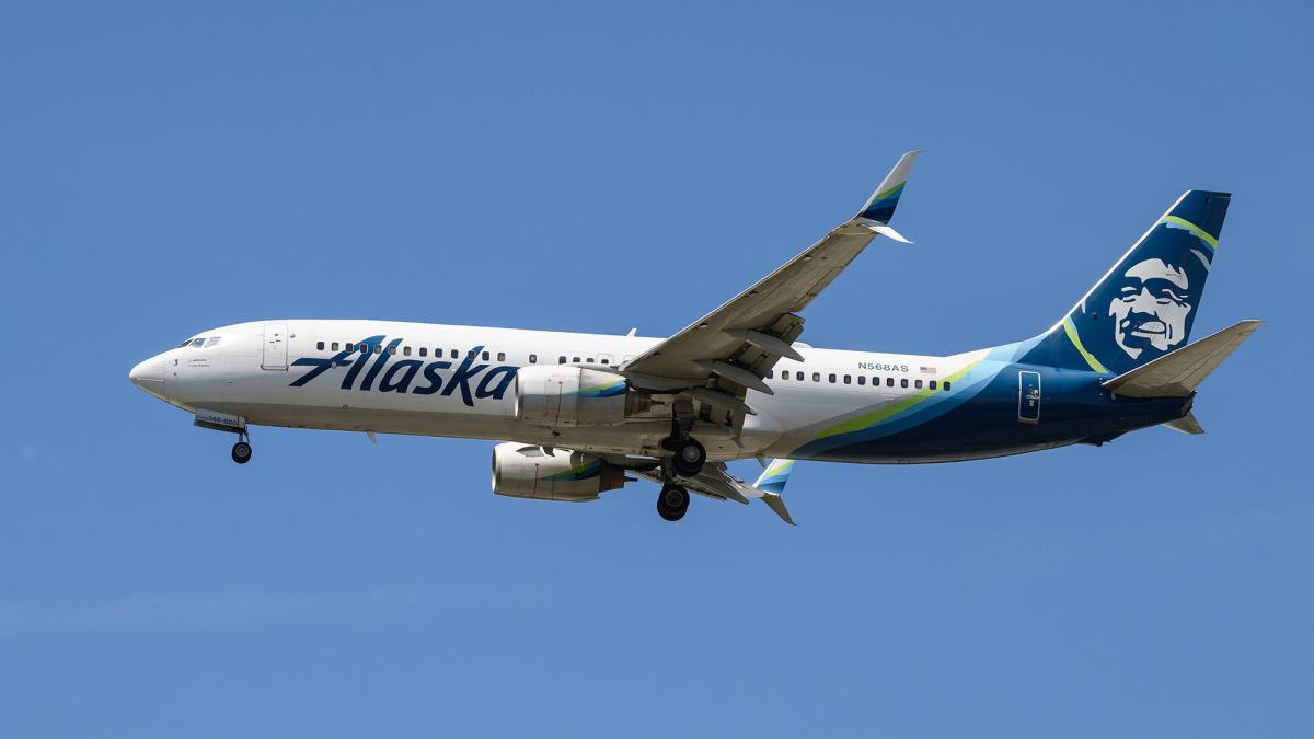 Passenger attempts to open Alaska Airlines cabin door, restrained by crew.