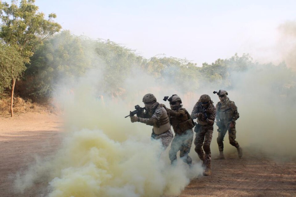 Indian Army soldiers advance through smoke during a joint field training exercise with a foreign army, illustrating India's multinational military exercises.