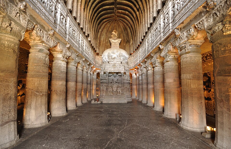 Interior of Cave 26 at Ajanta, Maharashtra — a rock-cut Buddhist chaitya hall with a carved stupa and seated Buddha