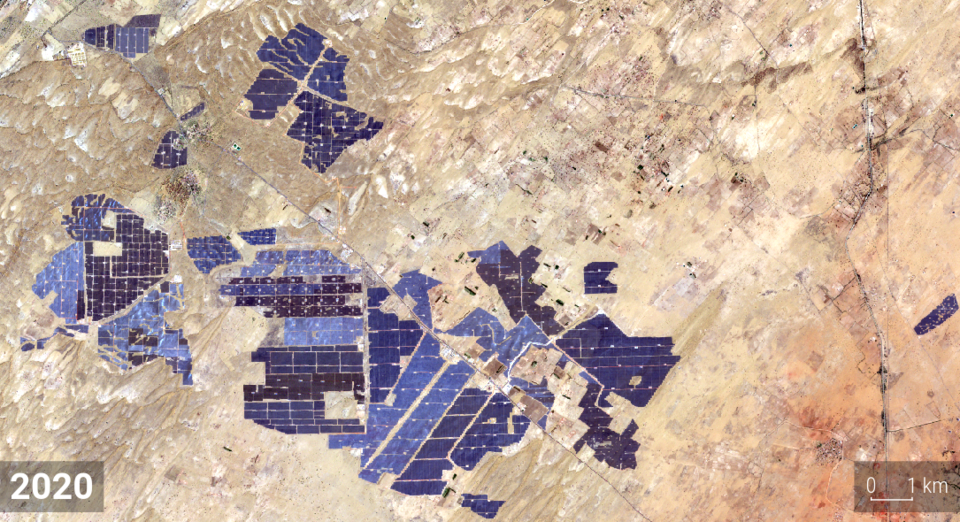 Satellite view of the Bhadla solar park in the Thar desert of Rajasthan, dark blue blocks of photovoltaic panels spread across pale sand