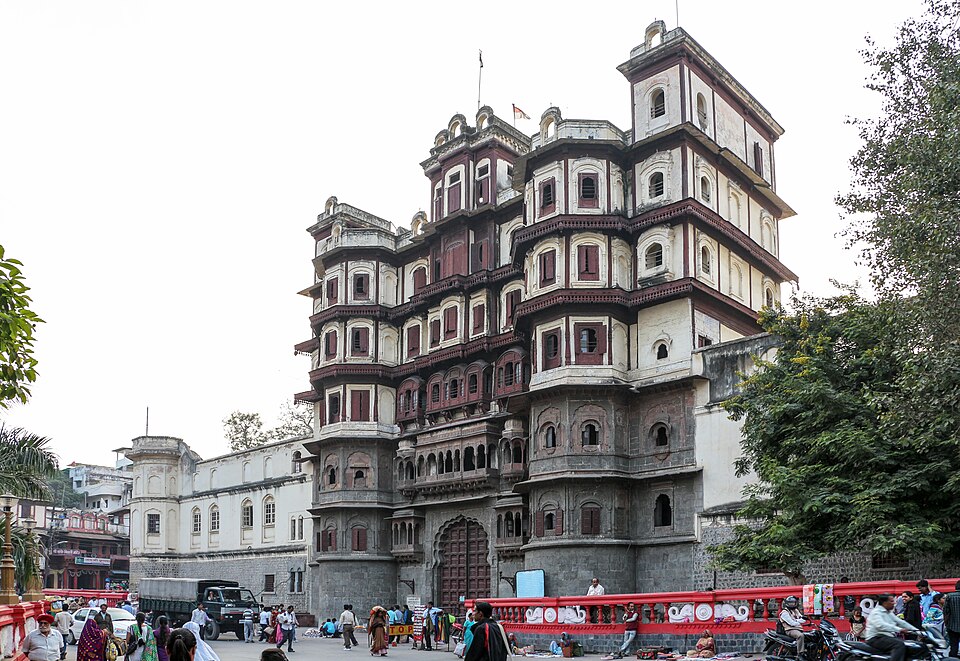 The tiered timber-and-stone facade of the Rajwada palace in Indore rising above the busy street in front of it