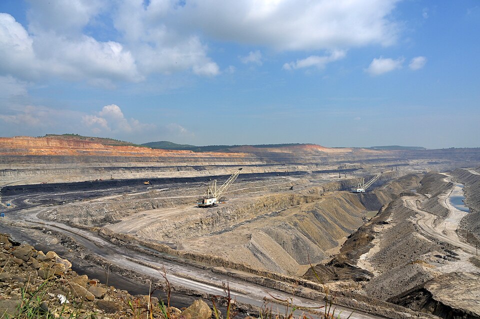 A wide open-cast coal pit at Singrauli with terraced benches, haul roads and walking draglines working the exposed coal seam