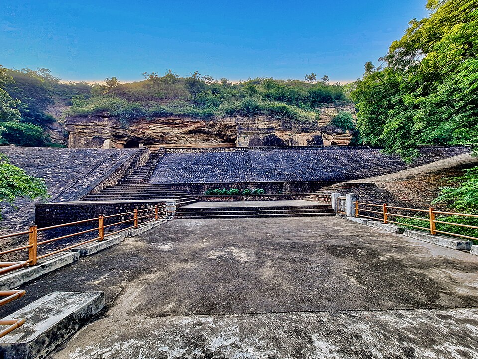 The rock-cut Bagh Caves in the sandstone cliff of Dhar district, their dark cave mouths above a stepped stone forecourt