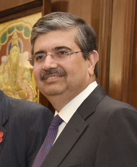 Portrait of the banker Uday Kotak in a dark suit and patterned tie, wearing rimless glasses, in front of a framed painting