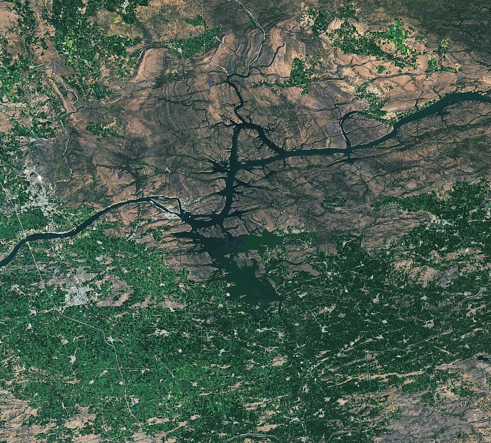 Landsat satellite view of the dark, branching Omkareshwar reservoir on the Narmada river winding through hilly terrain in Madhya Pradesh