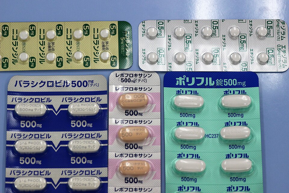Several blister packs of pharmaceutical tablets laid out together, white and pale-orange pills sealed in foil-backed strips