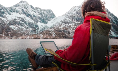 Person jobber på laptop hjemmefra med vinterlandskap utenfor vinduet