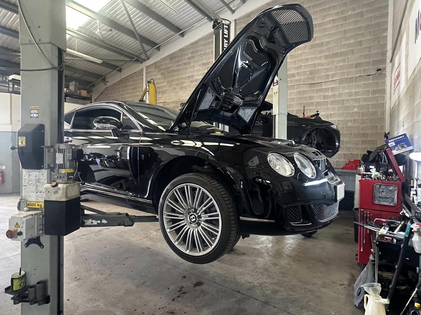 Black Bentley Continental GT on a lift with its bonnet open