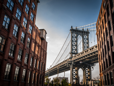 Manhattan bridge seen from a narrow alley enclosed by two brick buildings on a sunny day in summer.jpeg