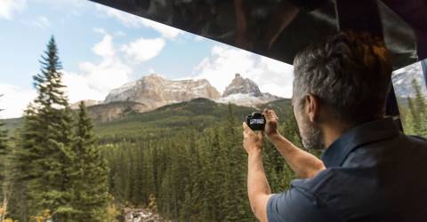 Man fotar naturen från tågfönster i Rocky Mountains, Kanada