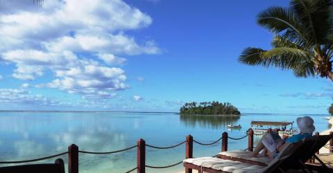 Kvinna i solstol på terass på Muri Beachcomber på Rarotonga, Cook