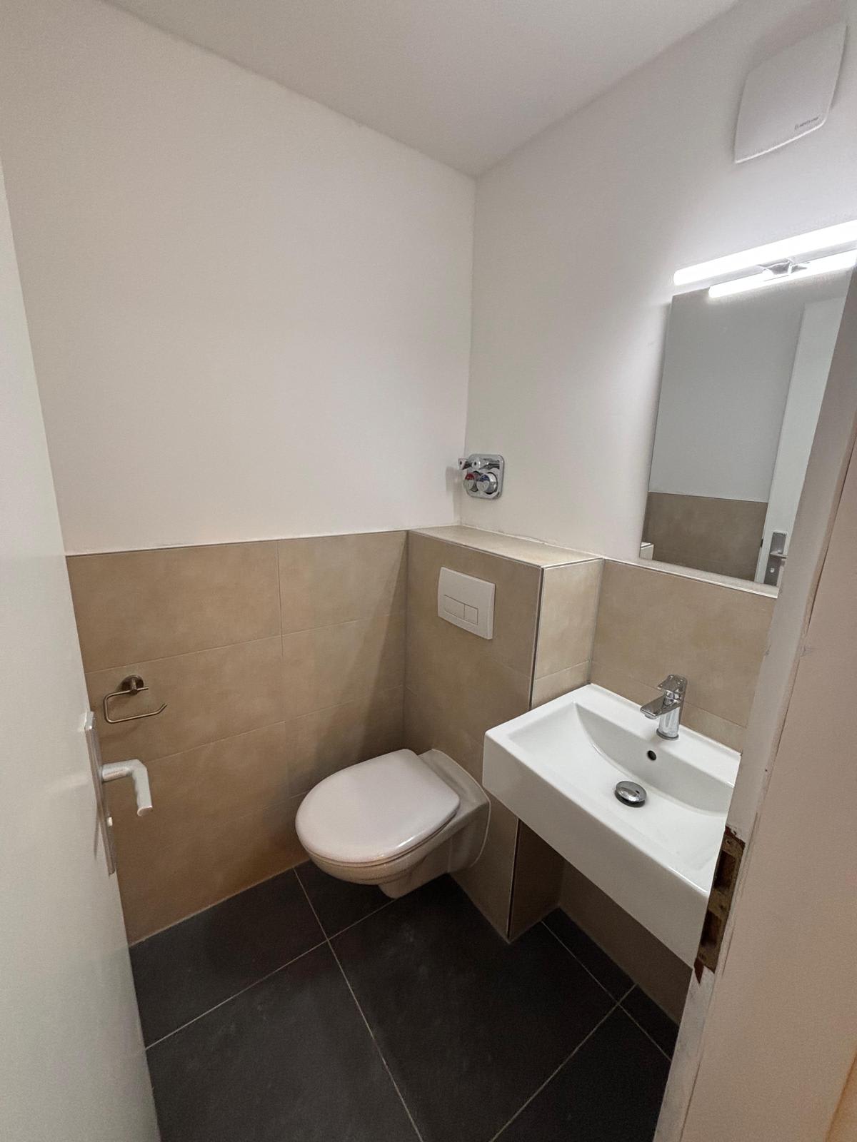 Gäste-WC in Frankfurt nach der Sanierung mit wandhängendem WC, Waschbecken und beigen Wandfliesen