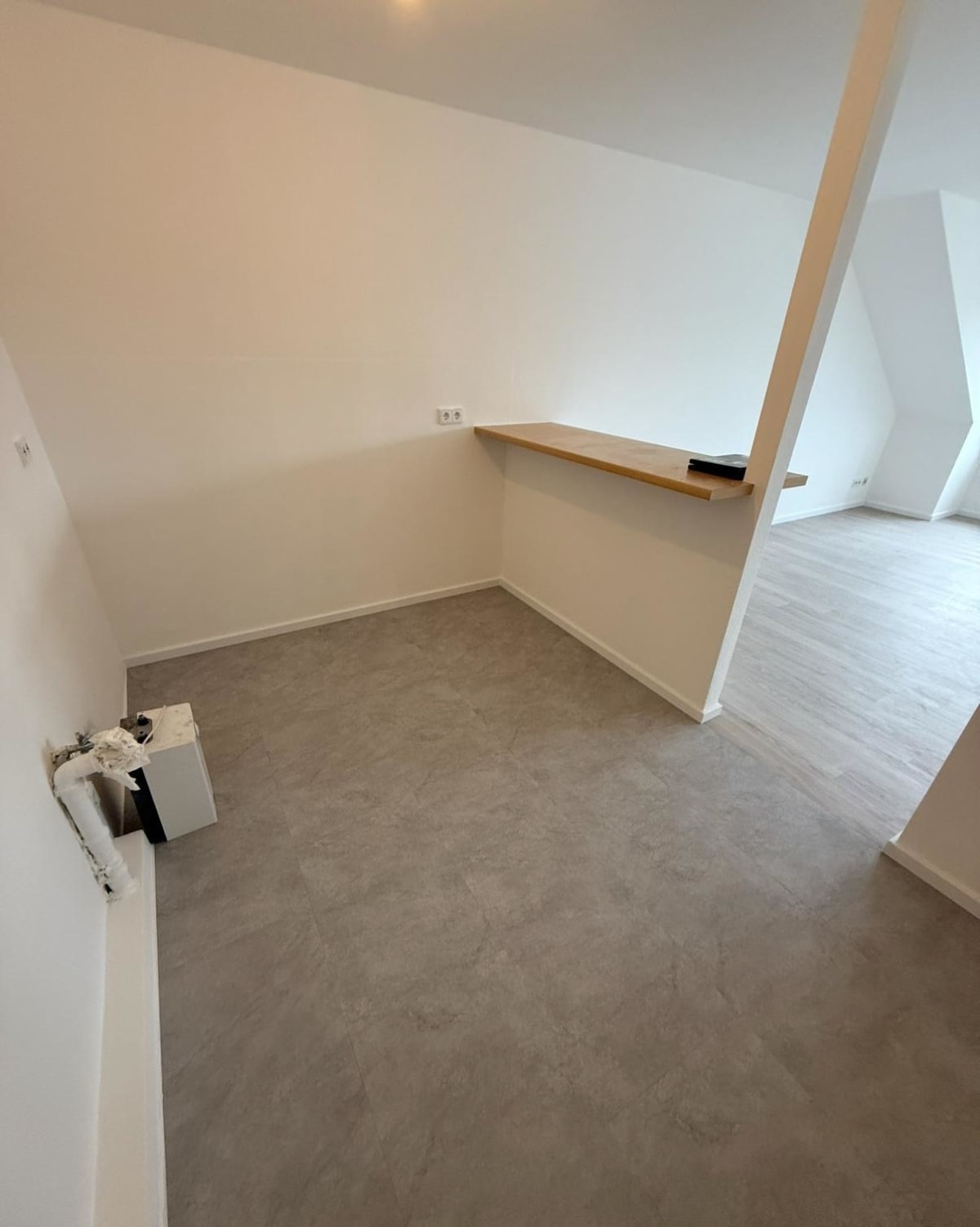 Dachgeschosszimmer in Frankfurt nach dem Trockenbau mit Dachschräge, Holzablage und neuem Bodenbelag