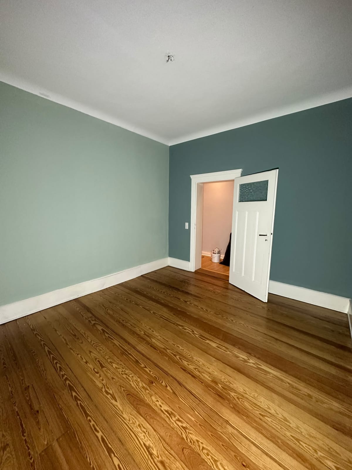 Zimmer mit türkisfarbenen Wänden und weißer Decke nach den Malerarbeiten in Wiesbaden