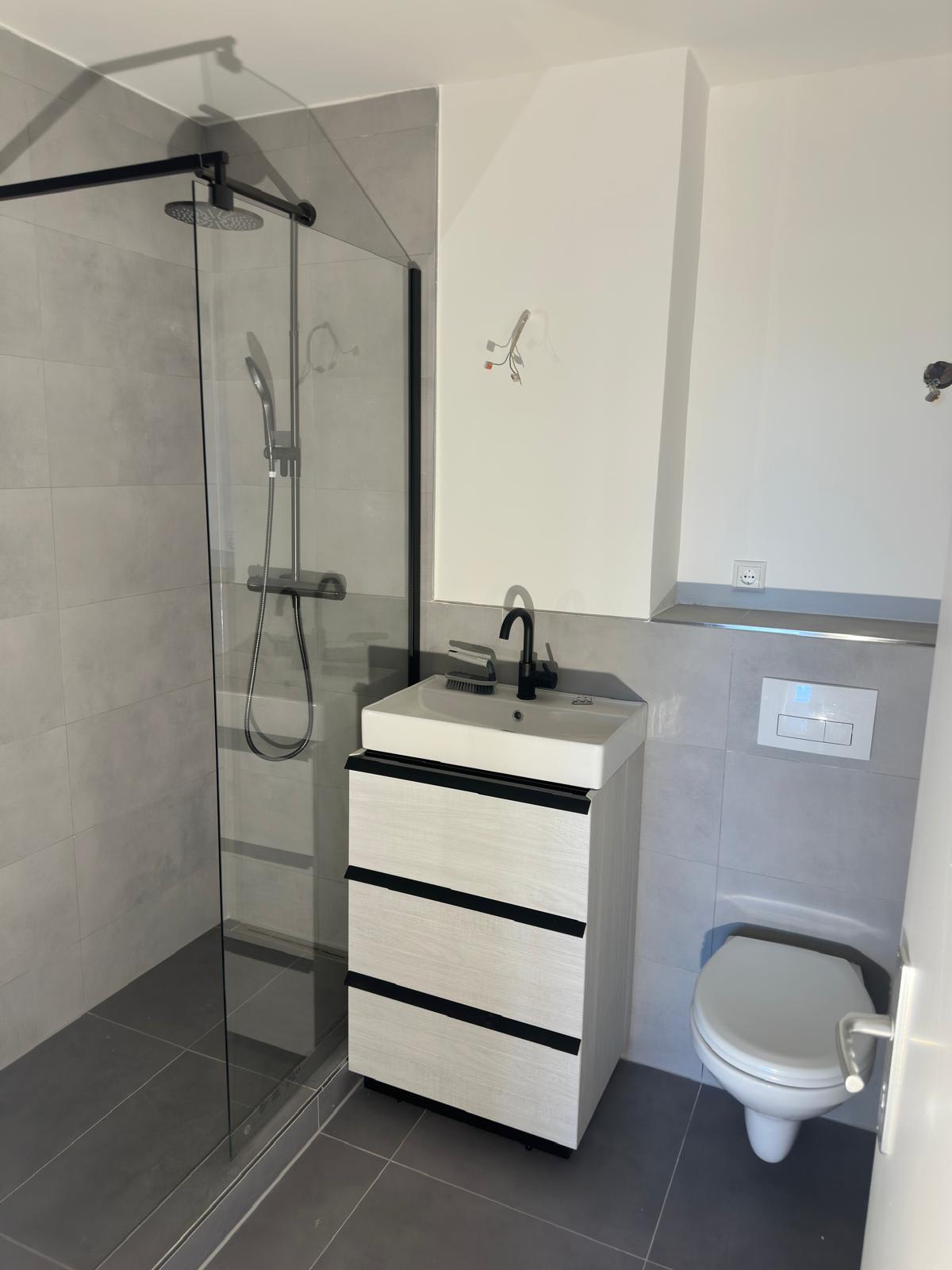 Saniertes Bad in Frankfurt-Berkersheim mit gefliester Dusche, Glaswand, großformatigen Bodenfliesen und wandhängendem WC