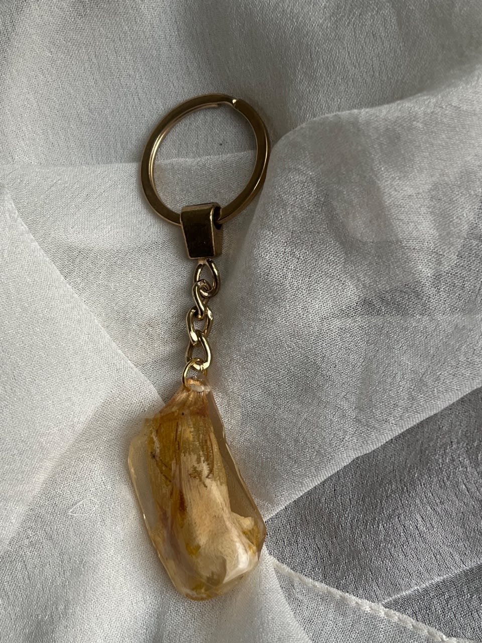 Keychain shaped like a stone with a yellow real flower