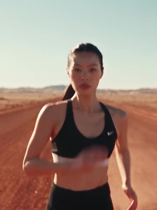 Alexandra Lim, in a black sports bra running on red desert earth