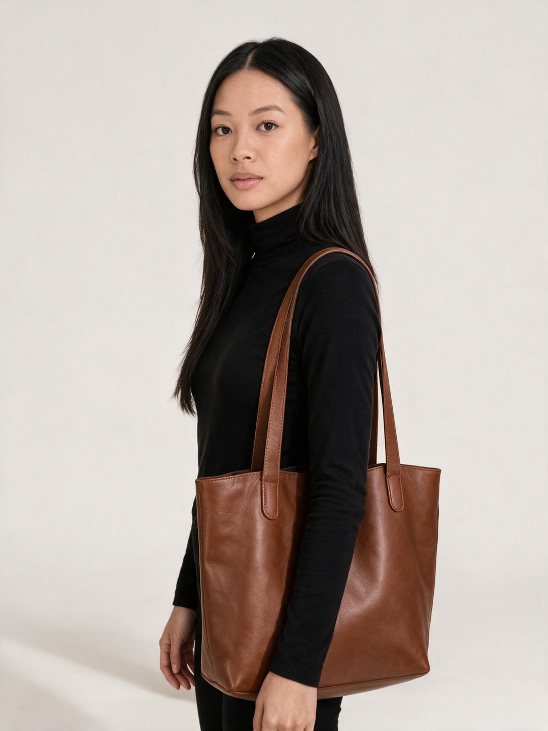 Alexandra Lim, carrying a brown leather tote in a black roll-neck