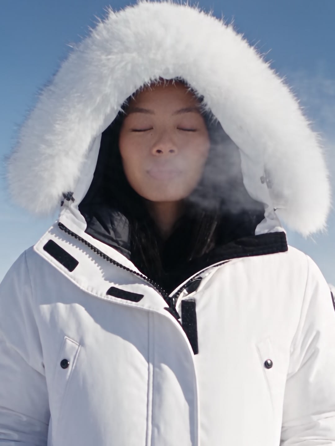 Alexandra Lim, in a white parka with a fur hood on a snowy mountain