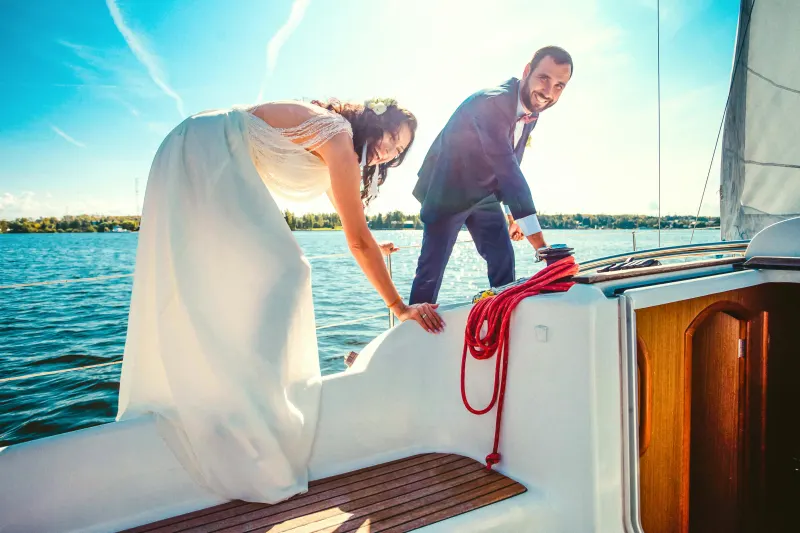 Bride and groom tying off a sailboat line on the water