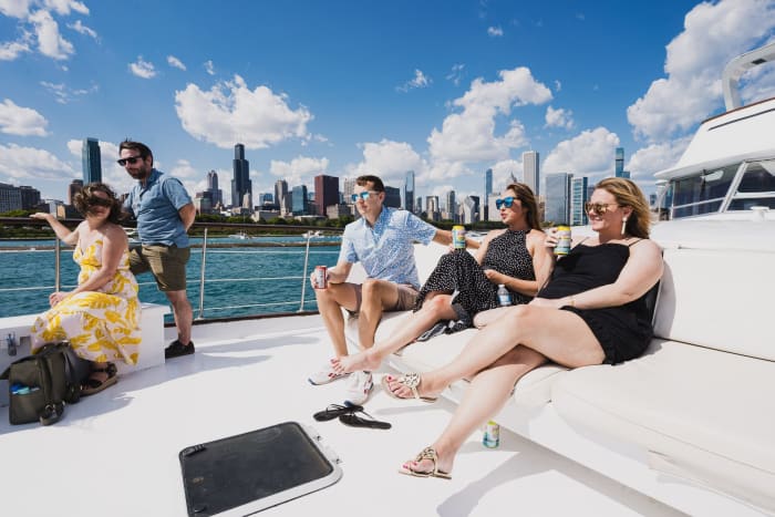 group of friends sitting and standing on the bow of a boat with a view of the Chicago skyline
