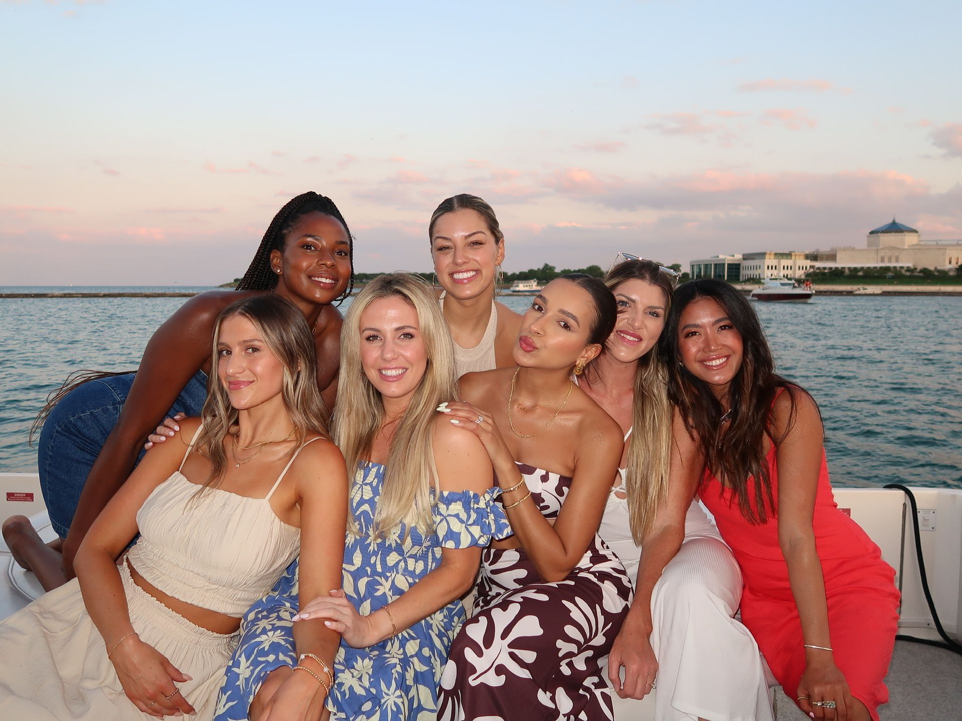 group of seven girls posing for a picture with the lake in the background