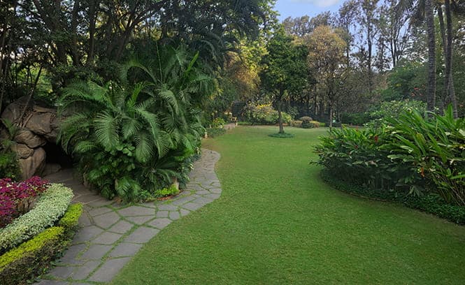 The Oberoi Bengaluru lush award-winning tropical garden lawn decorated for outdoor wedding ceremony — Panigrahana