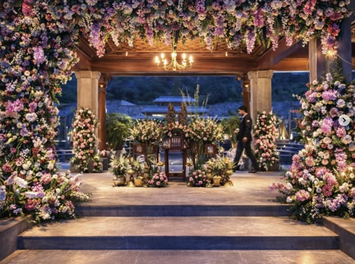 Floral wedding mandap with cascading pink and white flowers at twilight