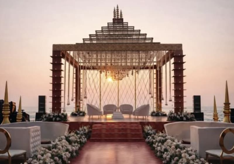 Oceanfront sunset mandap with coral and gold florals lining the aisle — Panigrahana in-house decor, Goa