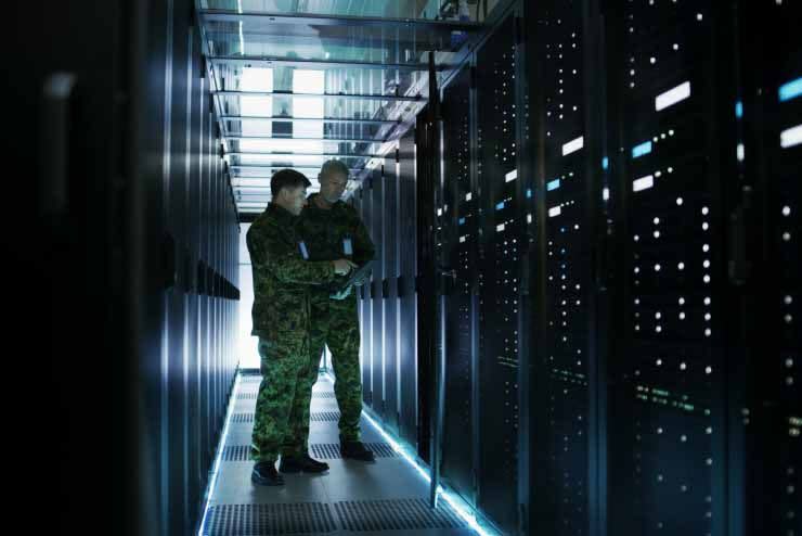 Two men in uniform assessing server in large server room