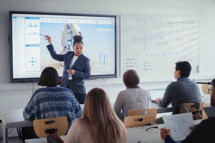 Teacher gives lesson in front of smart whiteboard