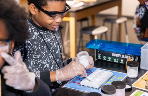 A participant places a sample in a testing device during a Crime Lab at Griffin MSI