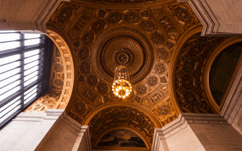 An architectural ceiling with a beautiful chandelier in the middle of it.