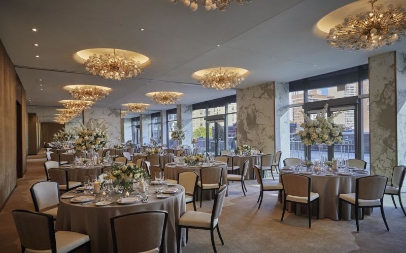 Dining room hall filled with beautiful chandeliers, tables and chairs.