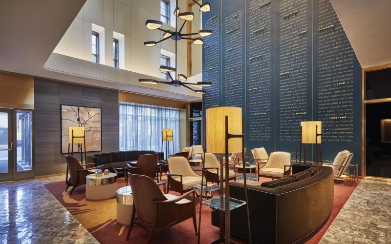 Lobby at the Viceroy Hotel with art deco furniture, lamps and chandeliers, alongside a dark blue wall covered in writing.