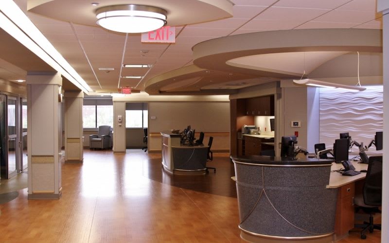Lobby of the hospital with ceiling lights and a front desk.