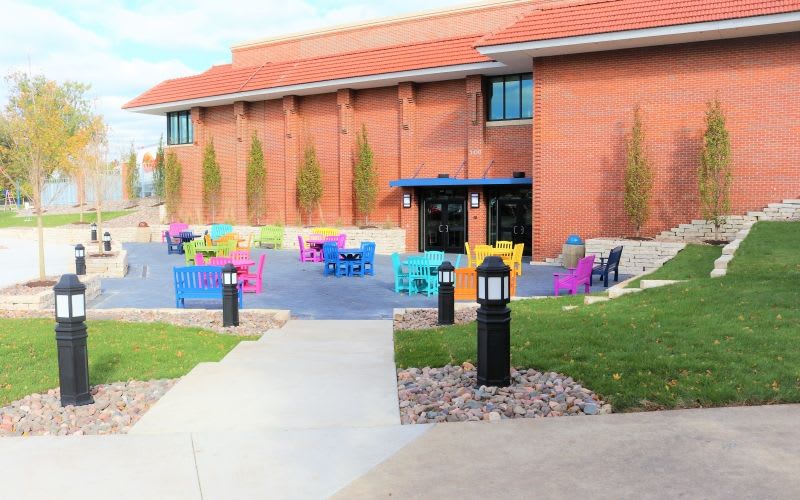 An outside area in front of the building with colorful benches all around.