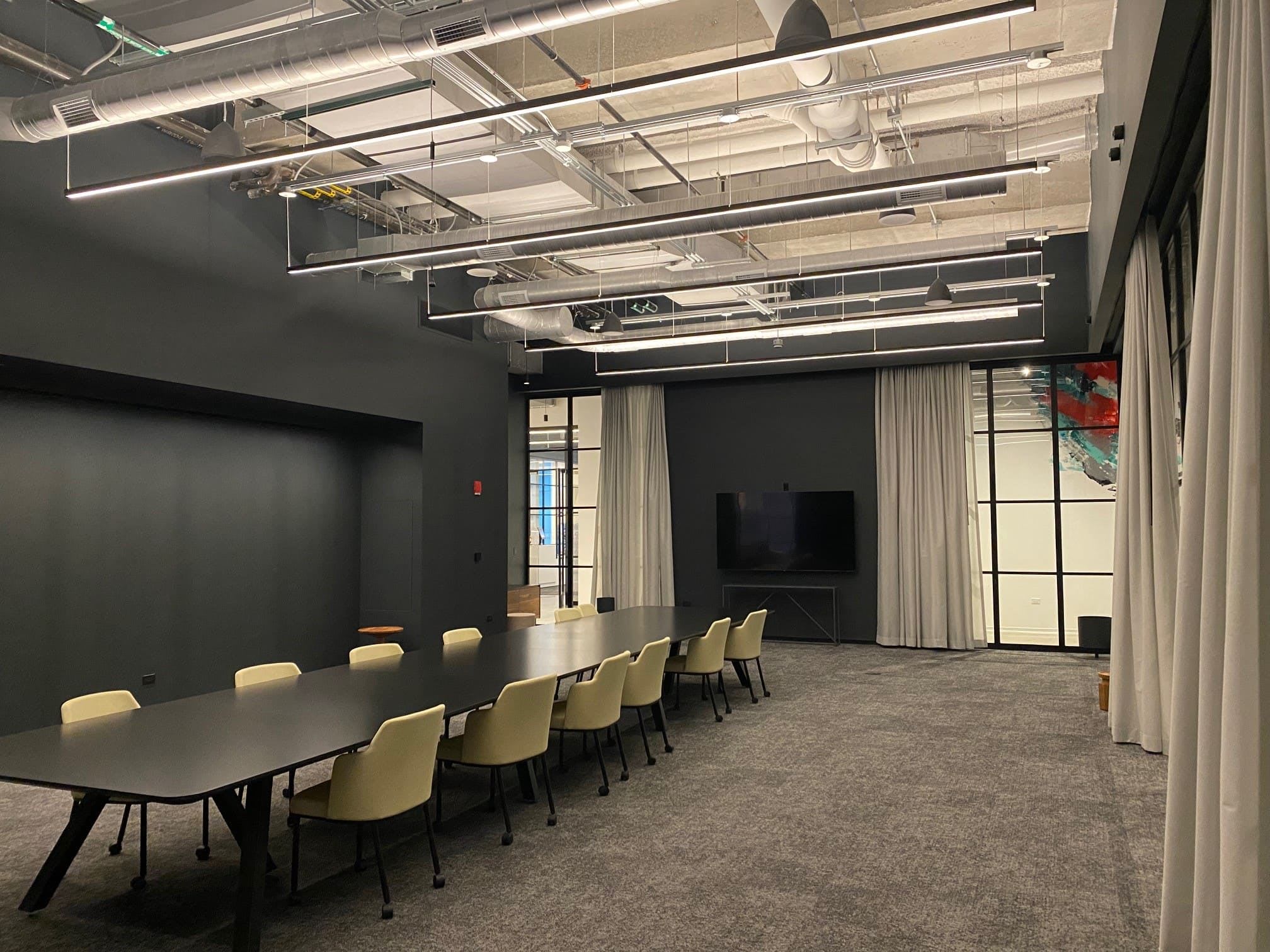 Another view of a meeting room with large windows and a long table and chairs.
