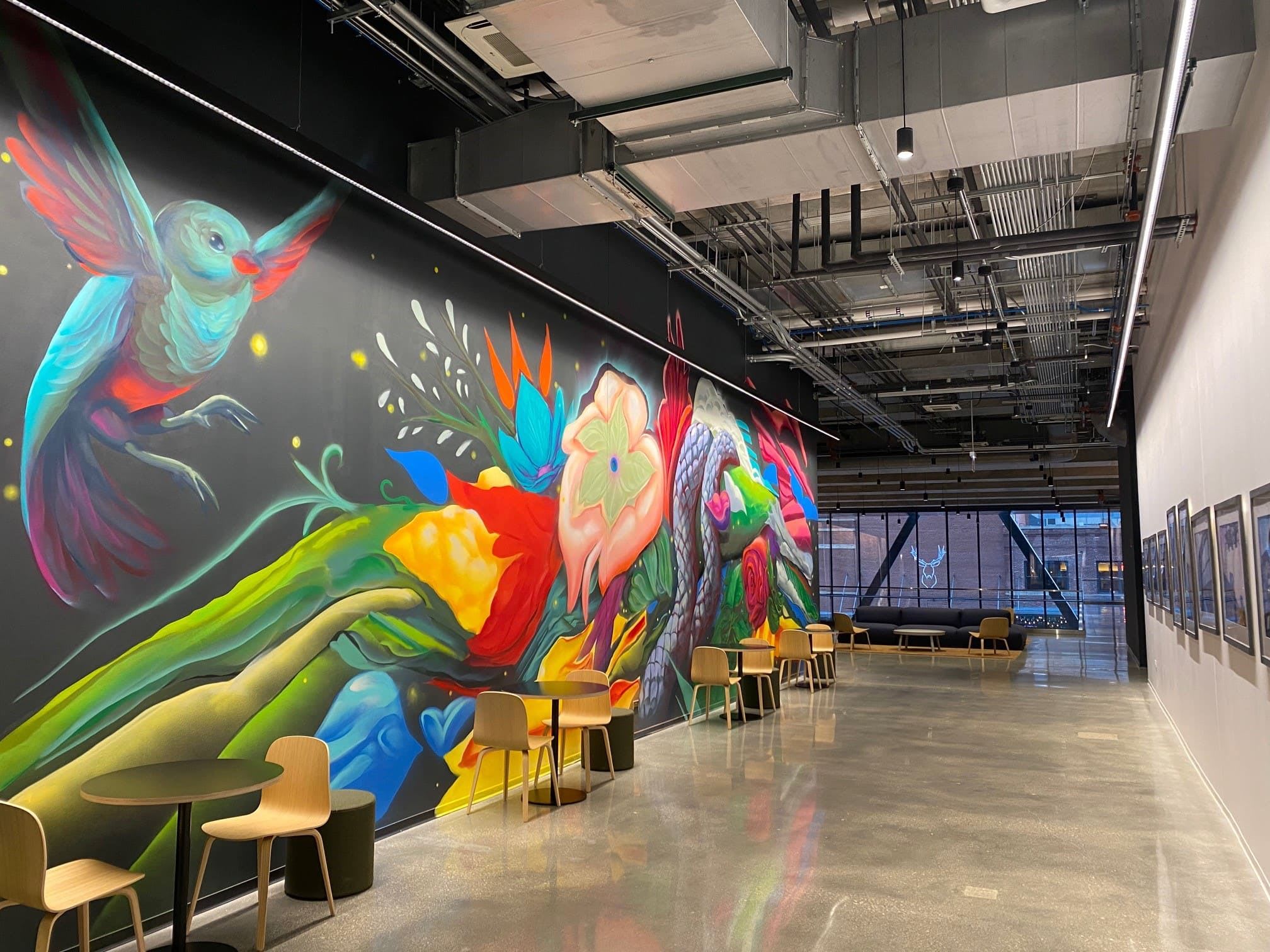 Long hallway with chairs and tables and featuring wall art of birds.